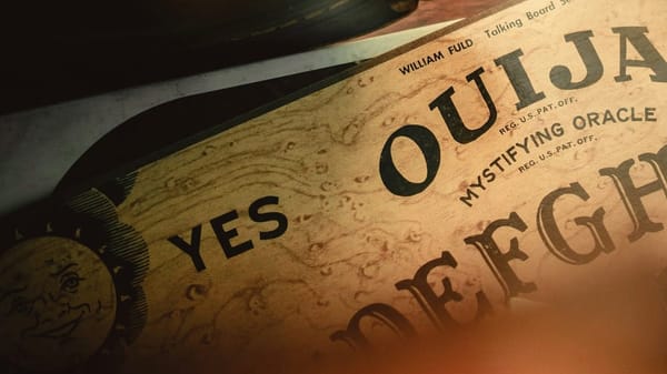 Close up of a Ouija board showing YES and the logo as well as some of the alphabet, blurring at the edges.